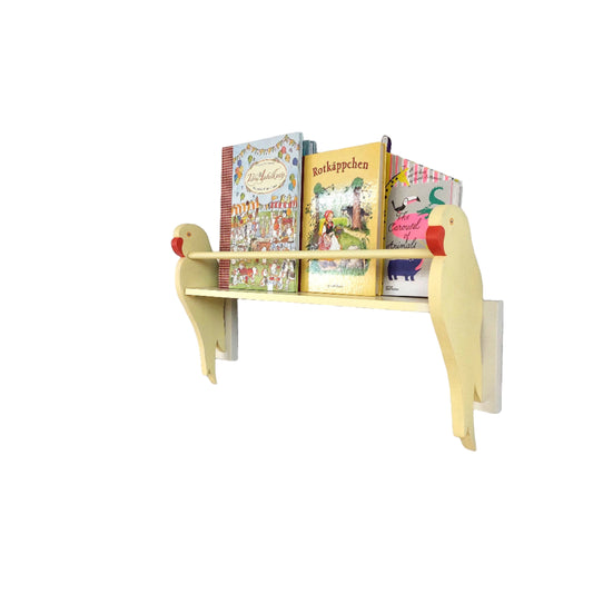 Yellow children's bookshelf in the design of a parrot against a white wall with books on it.